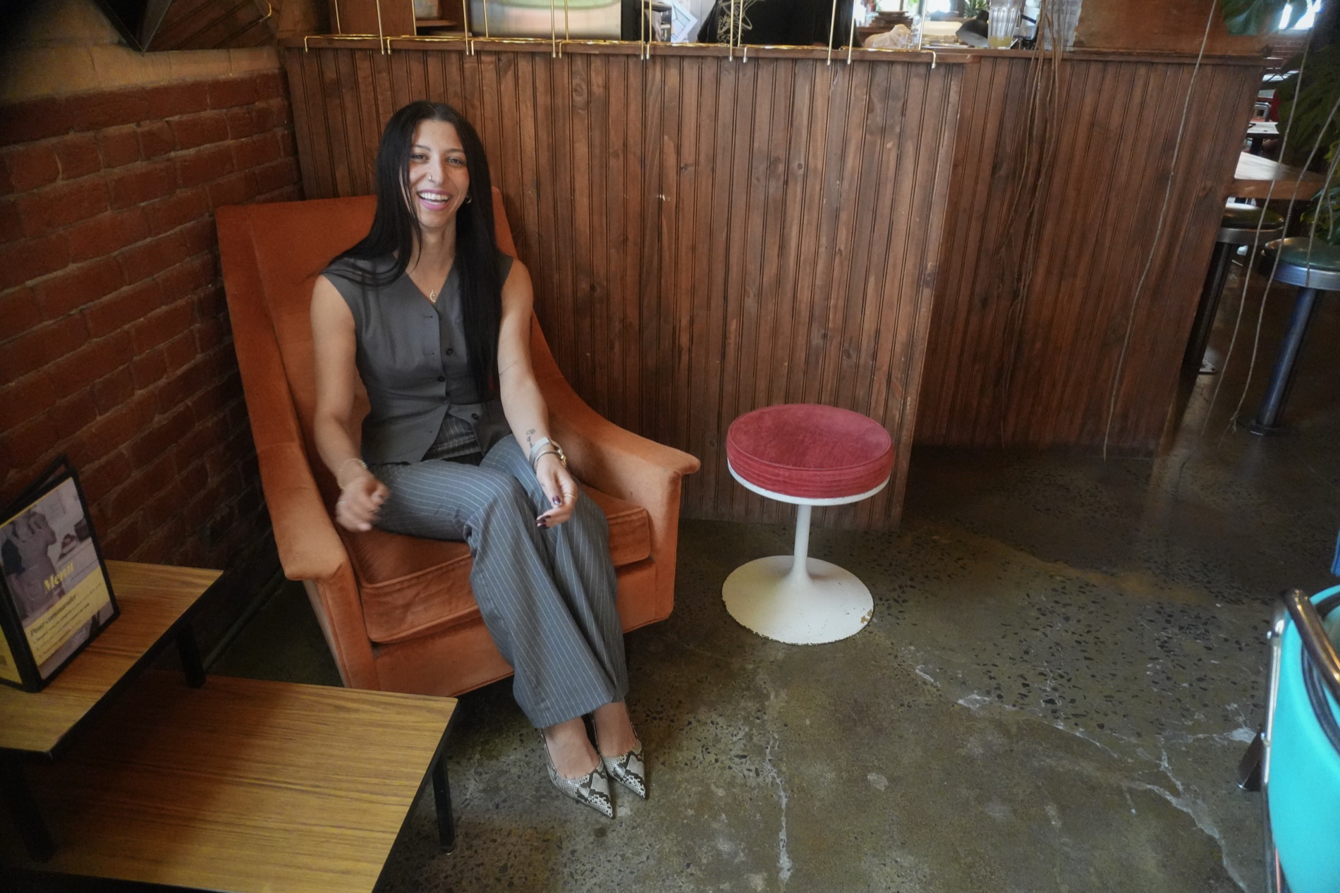 Meryem laughing in an orange velvet armchair in a Montreal café