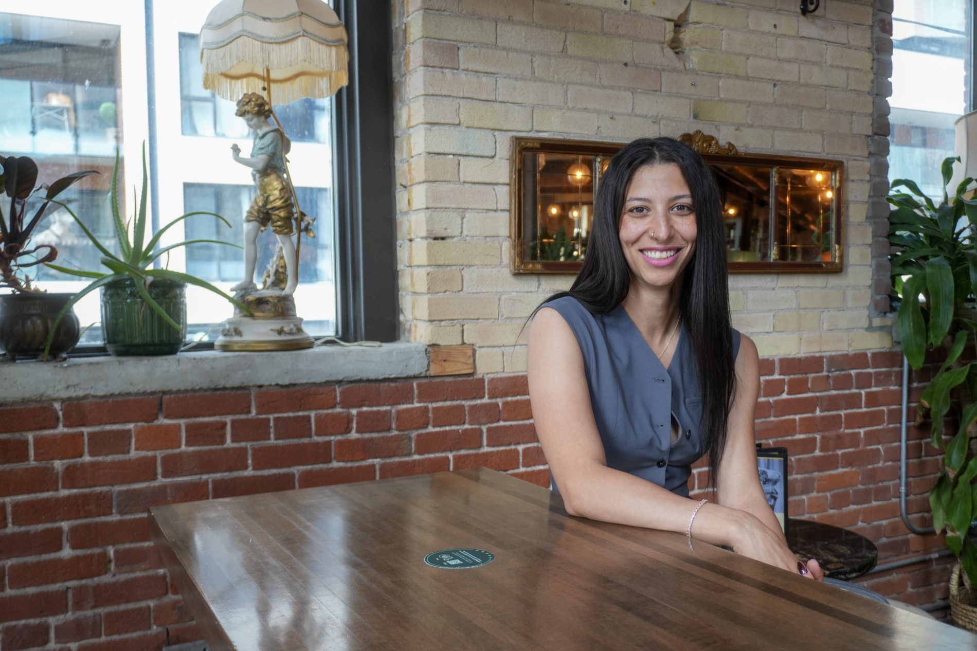 Meryem, a real estate broker, smiling at a café table in Montreal
