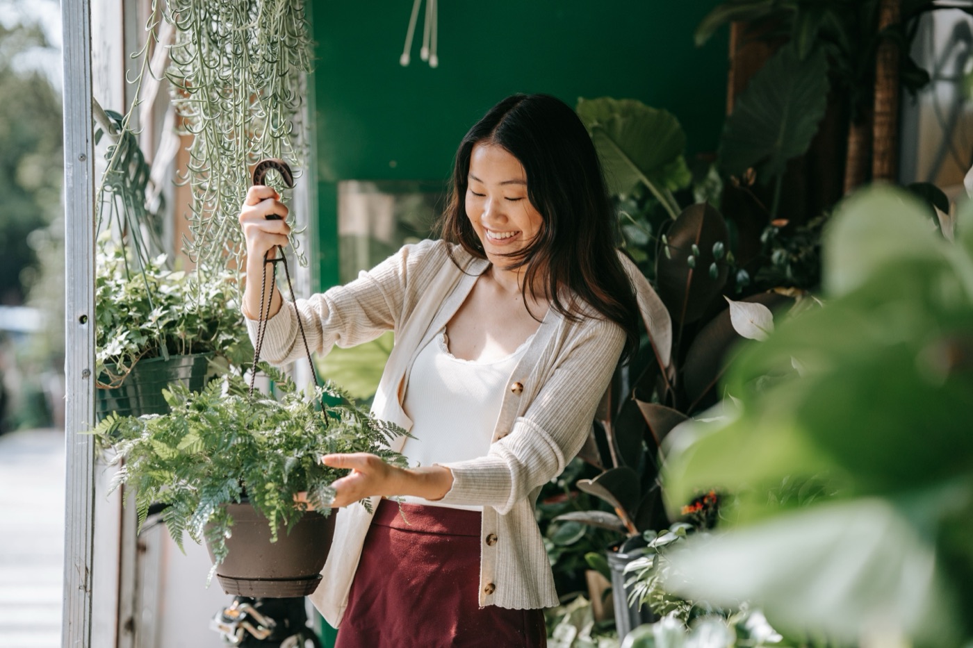 A florist tending hanging ferns outside her storefront